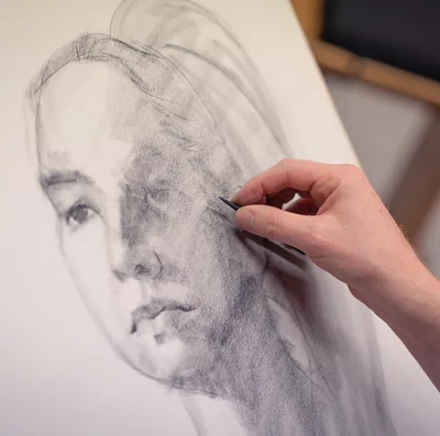 Students draws a portrait with charcoal