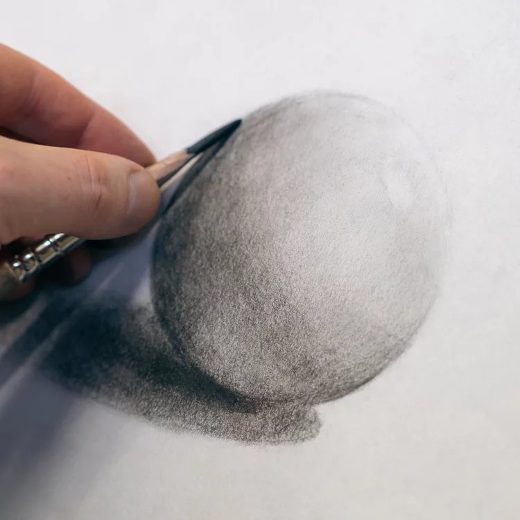 Hand mit Kohlestift zeichnet Kugel